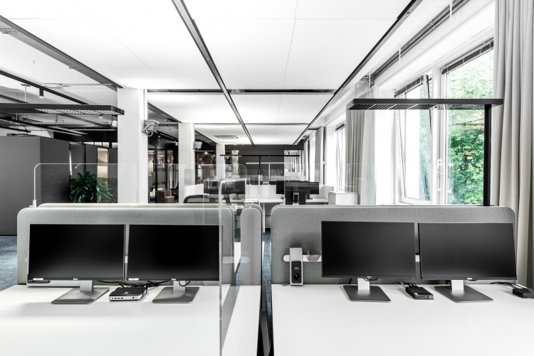 Moderner Arbeitsplatz mit Monitoren und Sichtschutzwänden im Open-Space Konzept