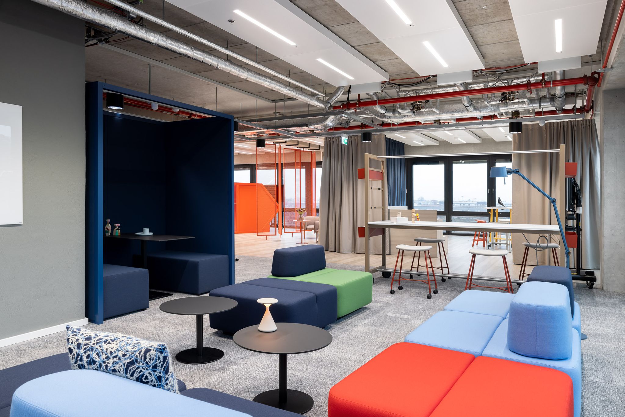 Sofas, Sitznische und Stehtisch in einem Büro. Verschiedene Farben.