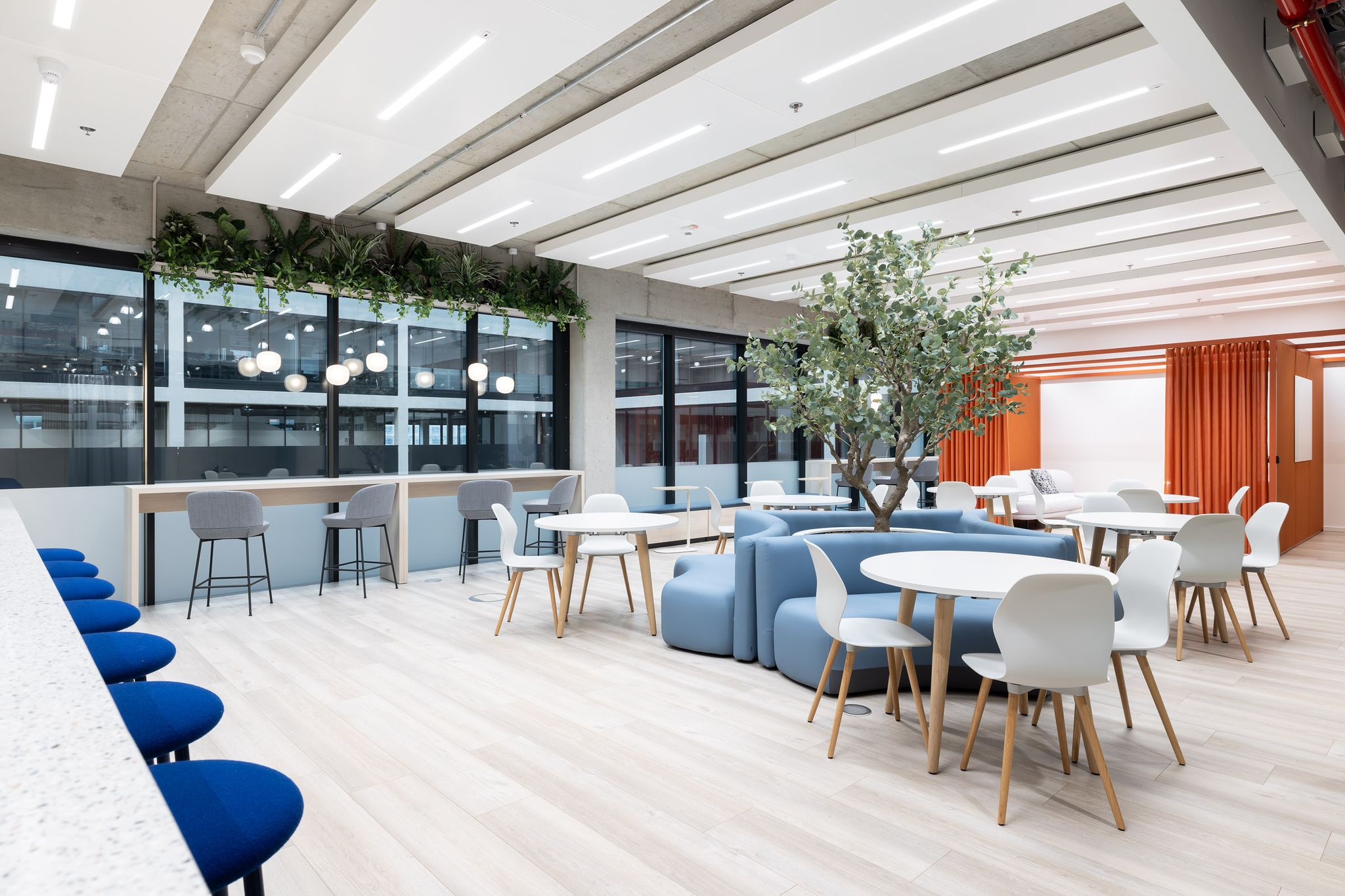 Sitzmöglichkeiten in einem Workcafe. Sofabänke und Stühle an runden Tischen