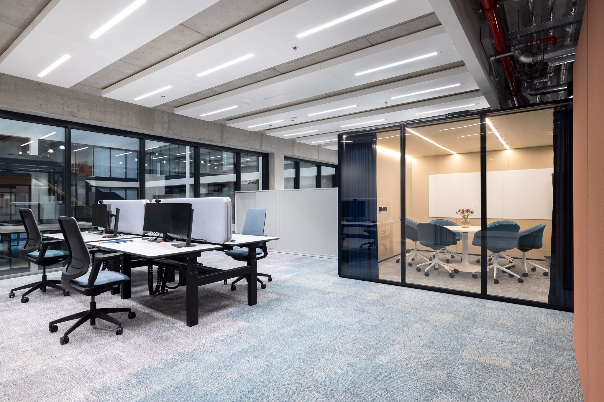 Arbeitstische und ein Raum-in-Raum-System mit Tisch und Stühlen