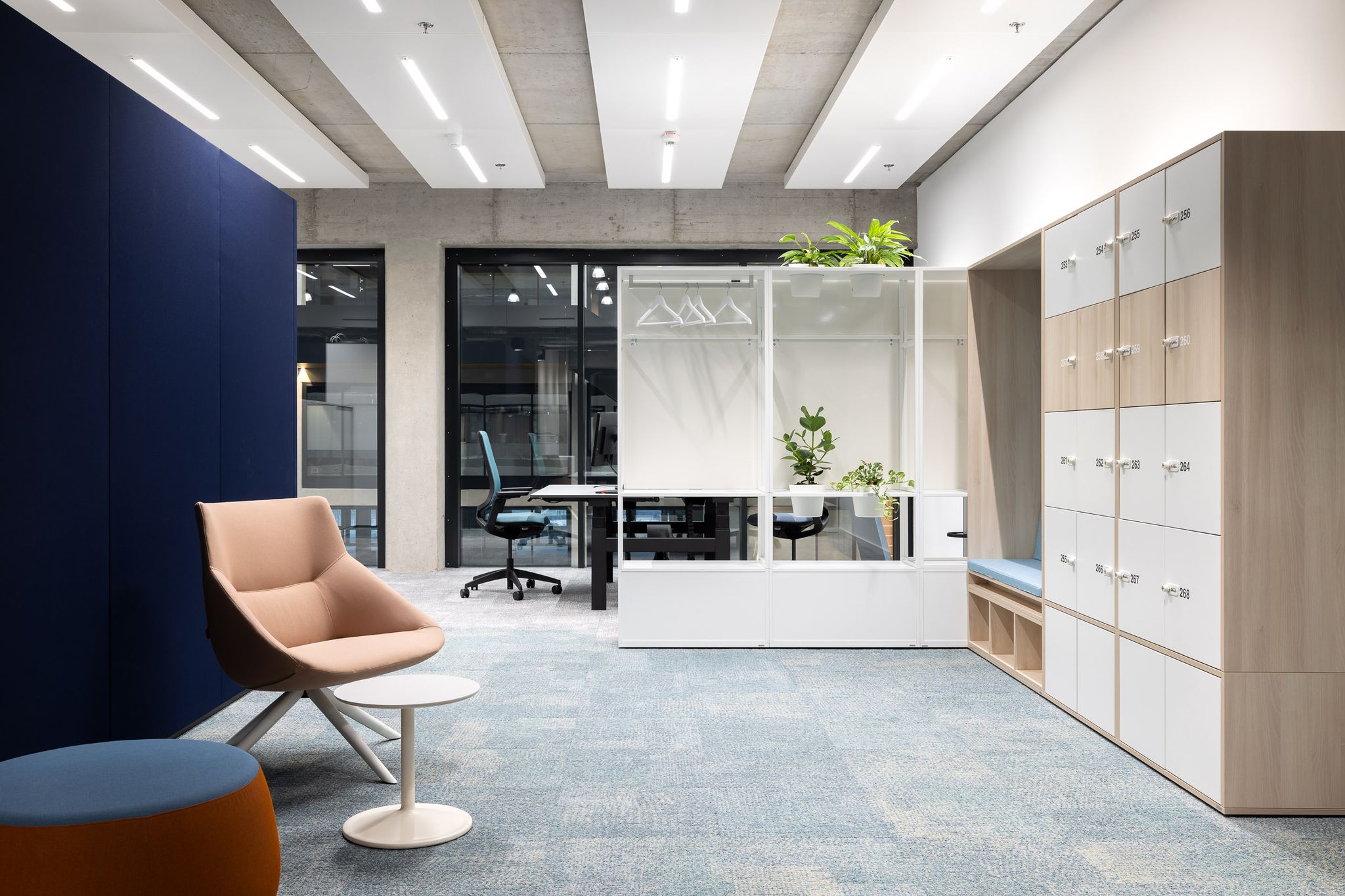 Blick in eine moderne Arbeitswelt mit Sessel und Beistelltisch sowie Schreibtisch im Hintergrund