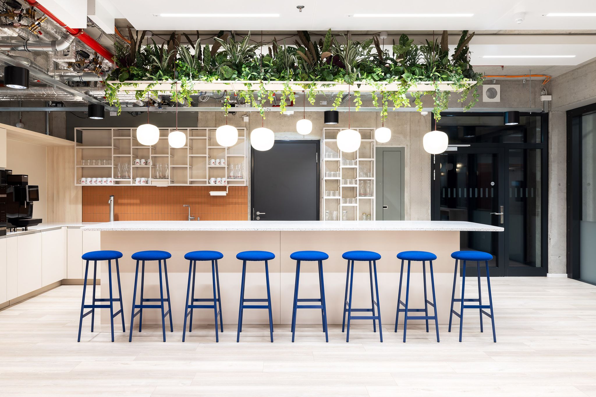 Küchentresen in hell mit Hängelampen und blauen Barhockern
