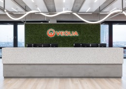 Empfangstheke, dahinter ein Veolia Schriftzug in rot auf grünem Mooshintegrund