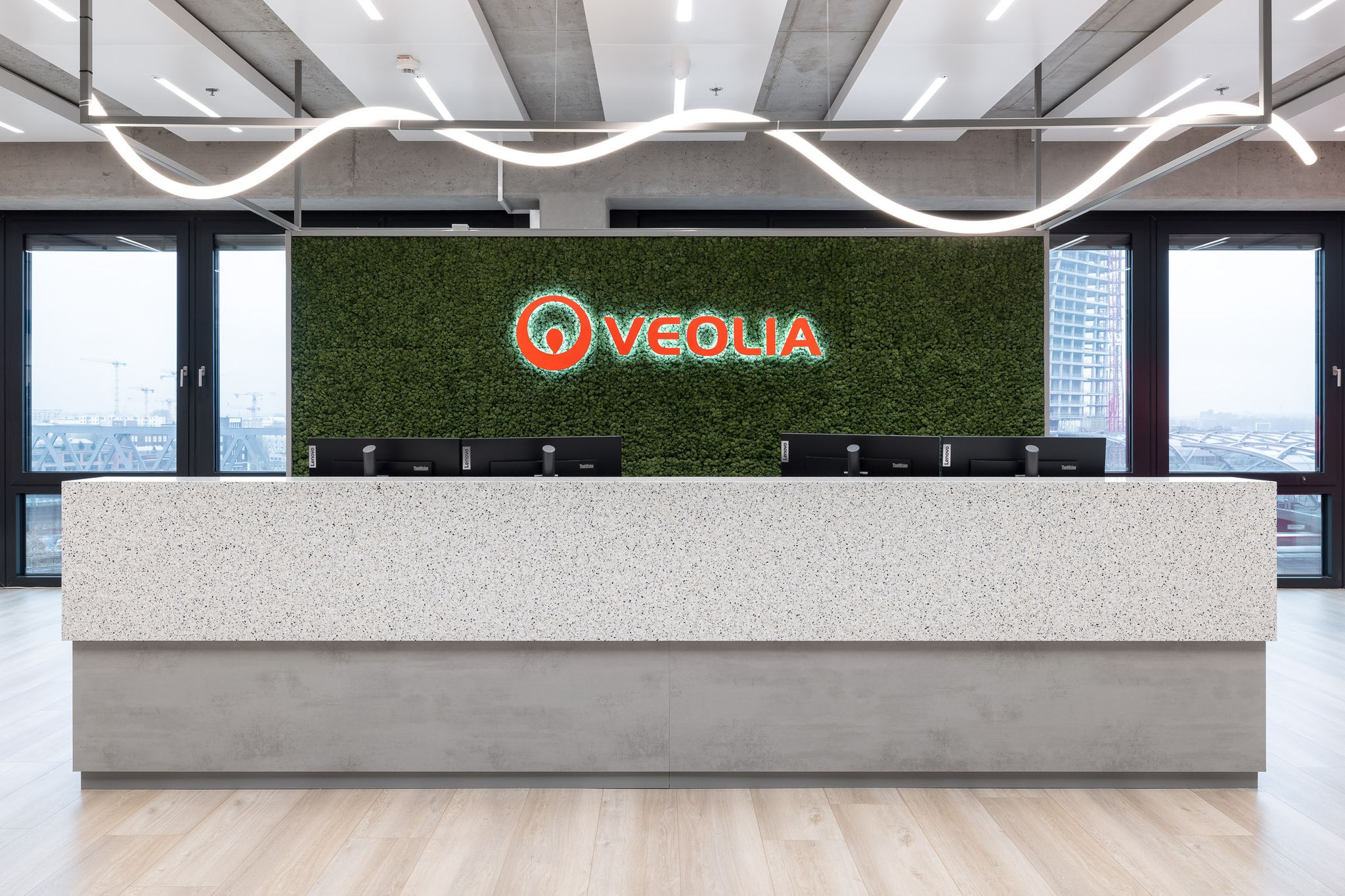 Empfangstheke, dahinter ein Veolia Schriftzug in rot auf grünem Mooshintegrund